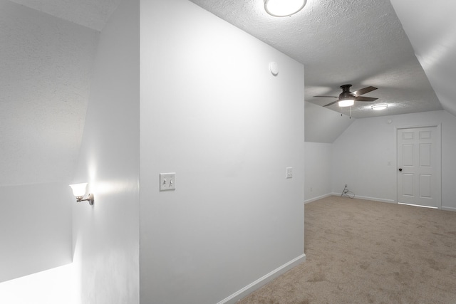 additional living space with ceiling fan, lofted ceiling, carpet floors, and a textured ceiling