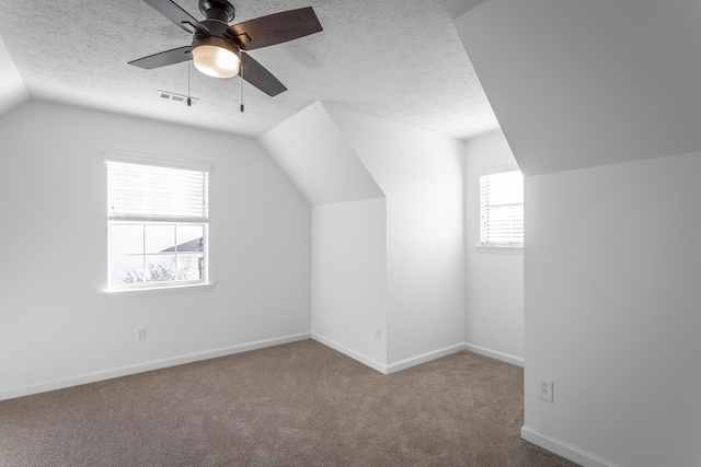 bonus room featuring ceiling fan, vaulted ceiling, a textured ceiling, and carpet flooring