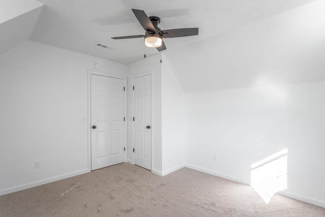 unfurnished bedroom featuring light carpet, ceiling fan, lofted ceiling, and a textured ceiling