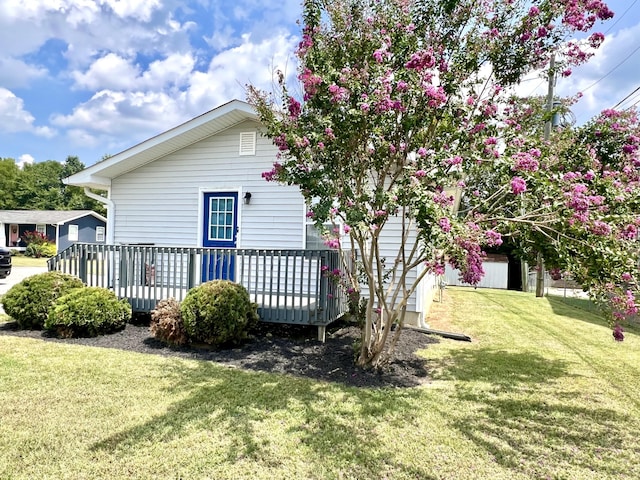 exterior space featuring a wooden deck and a lawn