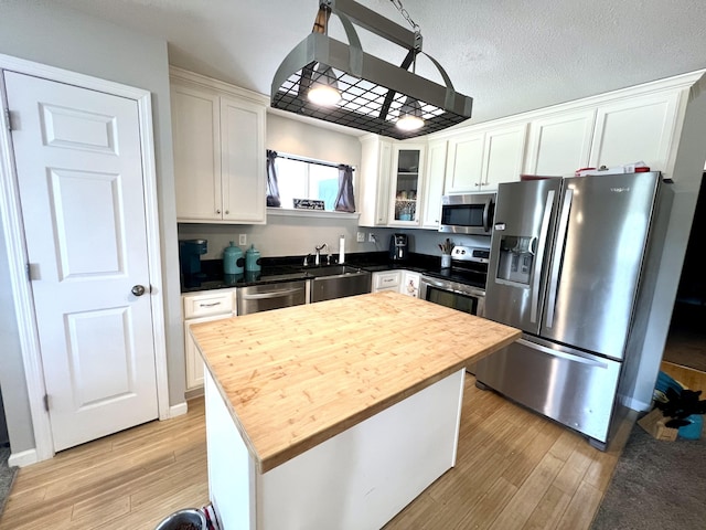 kitchen featuring a kitchen island, appliances with stainless steel finishes, white cabinets, and wood counters