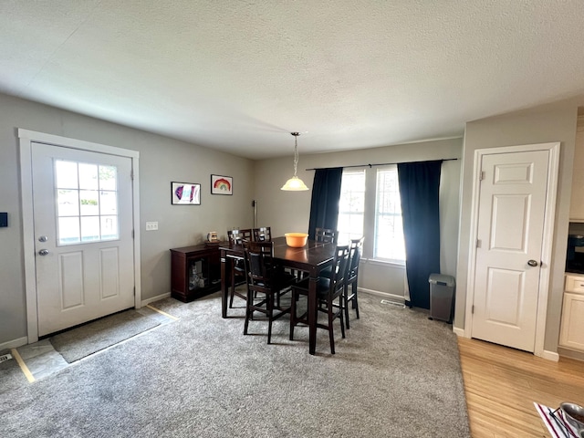 dining space featuring light hardwood / wood-style floors and a textured ceiling