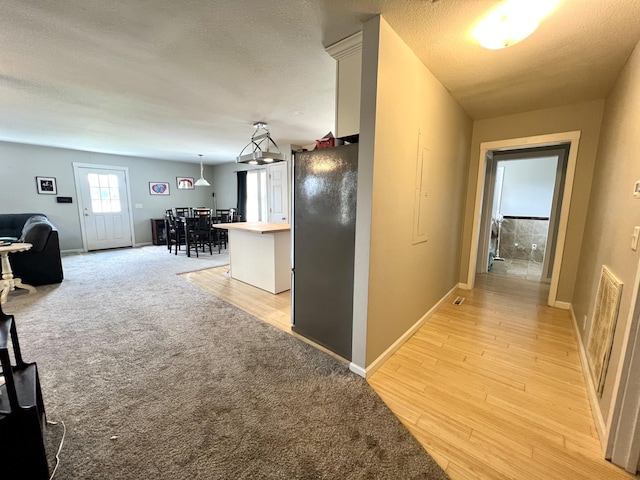 corridor with light colored carpet and a textured ceiling