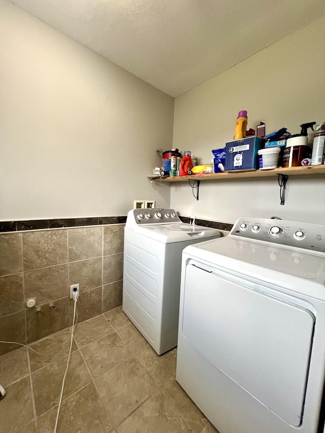 washroom featuring tile walls, tile patterned flooring, and washing machine and dryer