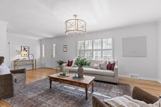 living room with an inviting chandelier, crown molding, and light hardwood / wood-style floors