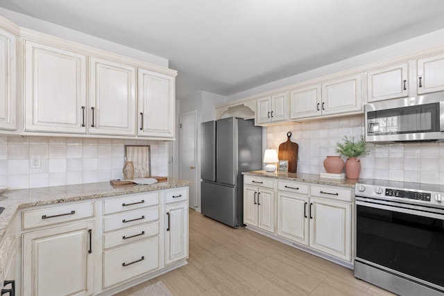 kitchen with backsplash, cream cabinets, and stainless steel appliances