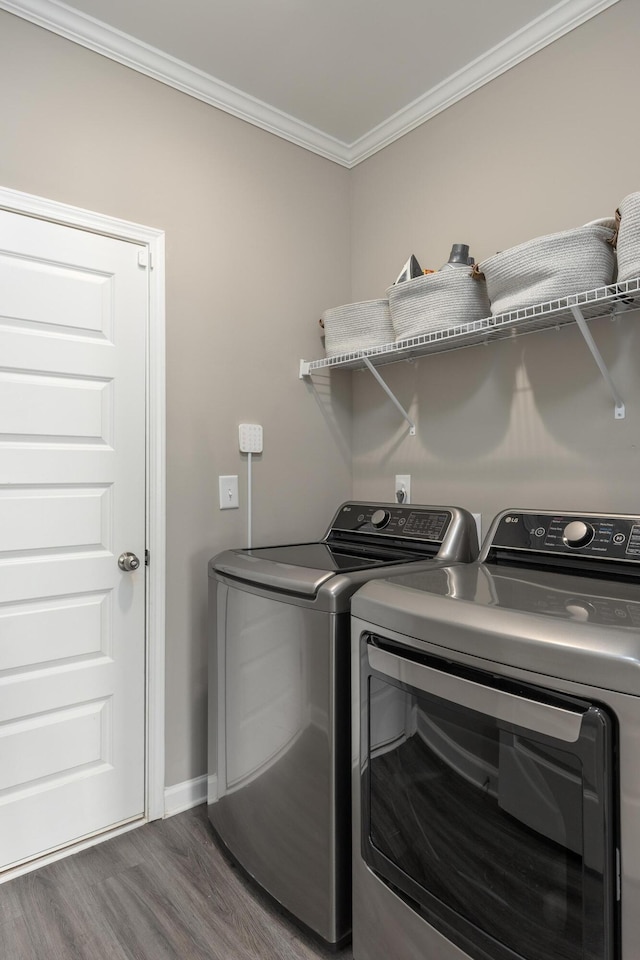 washroom featuring washing machine and clothes dryer, ornamental molding, wood finished floors, laundry area, and baseboards