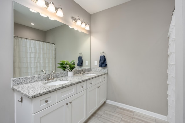 bathroom with a sink, baseboards, and double vanity