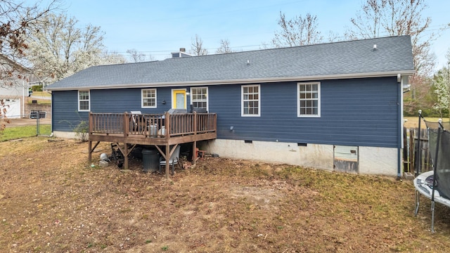 rear view of property with a deck, a trampoline, fence, a shingled roof, and crawl space