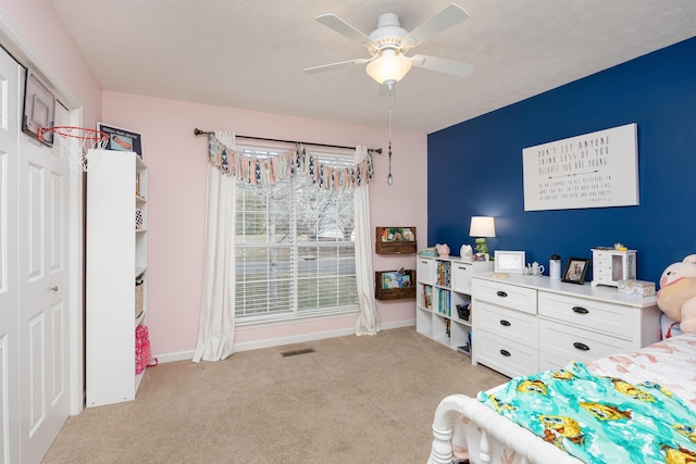 bedroom with light carpet, visible vents, a textured ceiling, and baseboards