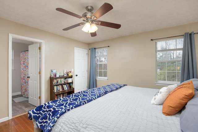 bedroom with multiple windows, a ceiling fan, baseboards, and wood finished floors