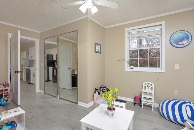 interior space with light wood-style floors, a textured ceiling, ornamental molding, and a ceiling fan