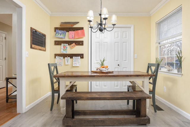 dining area with visible vents, baseboards, ornamental molding, light wood-style floors, and a notable chandelier