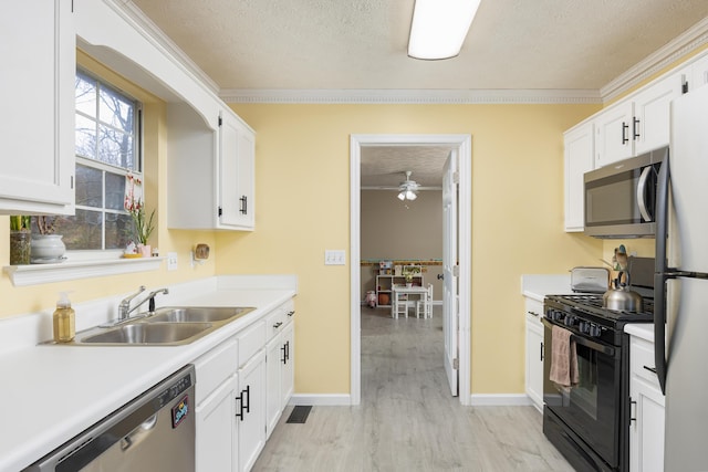 kitchen featuring a sink, a textured ceiling, white cabinetry, and stainless steel appliances