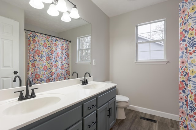 bathroom with baseboards, wood finished floors, visible vents, and a sink