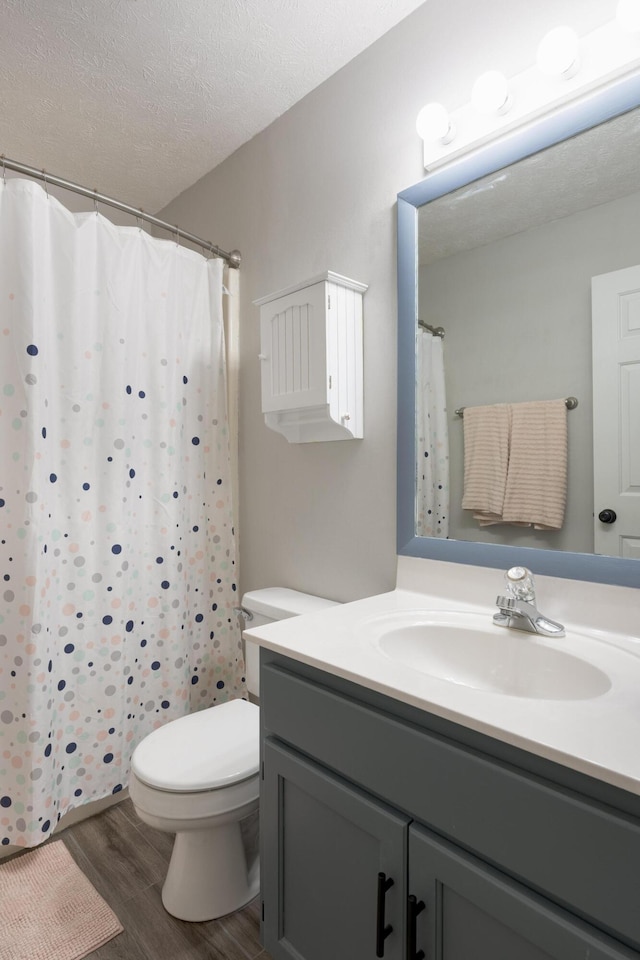 bathroom featuring toilet, curtained shower, a textured ceiling, wood finished floors, and vanity