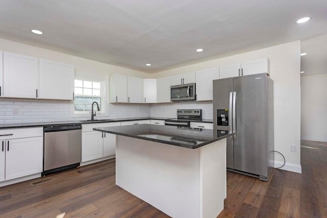 kitchen with sink, dark wood-type flooring, stainless steel appliances, a center island, and white cabinets