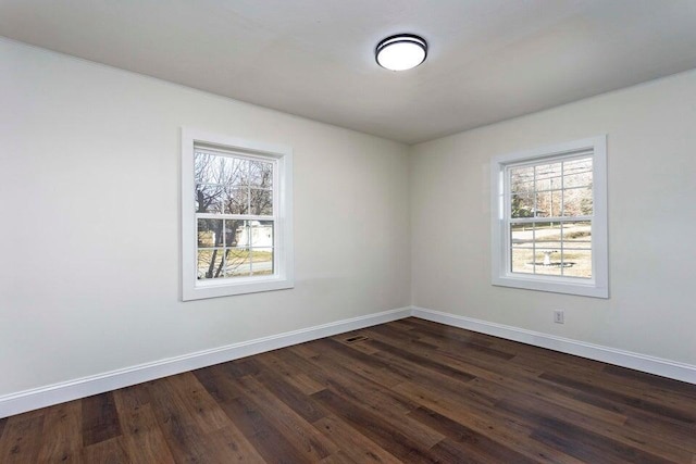 unfurnished room featuring a wealth of natural light and dark hardwood / wood-style flooring