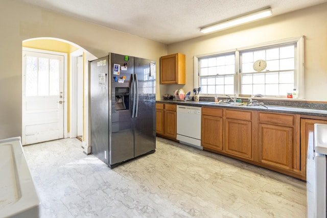 kitchen with stainless steel refrigerator with ice dispenser, dishwasher, sink, and a textured ceiling