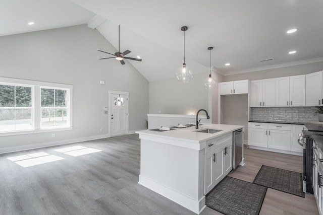 kitchen with sink, tasteful backsplash, an island with sink, white cabinets, and decorative light fixtures