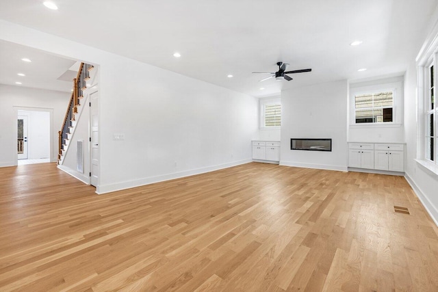 unfurnished living room featuring ceiling fan and light wood-type flooring