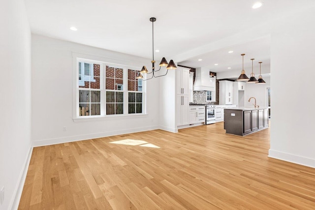 unfurnished dining area with sink, a notable chandelier, and light wood-type flooring