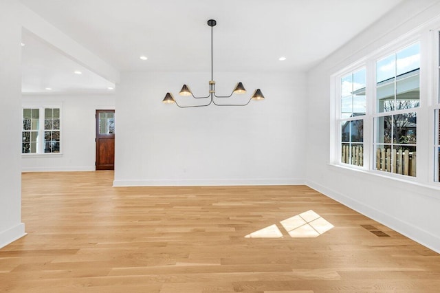 unfurnished dining area featuring an inviting chandelier and light hardwood / wood-style flooring