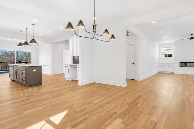 kitchen featuring an island with sink, a wealth of natural light, pendant lighting, light hardwood / wood-style floors, and white cabinets