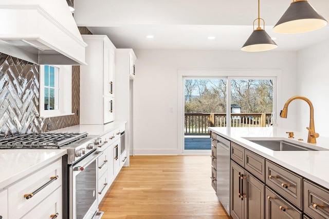 kitchen with pendant lighting, white cabinetry, sink, custom exhaust hood, and stainless steel appliances