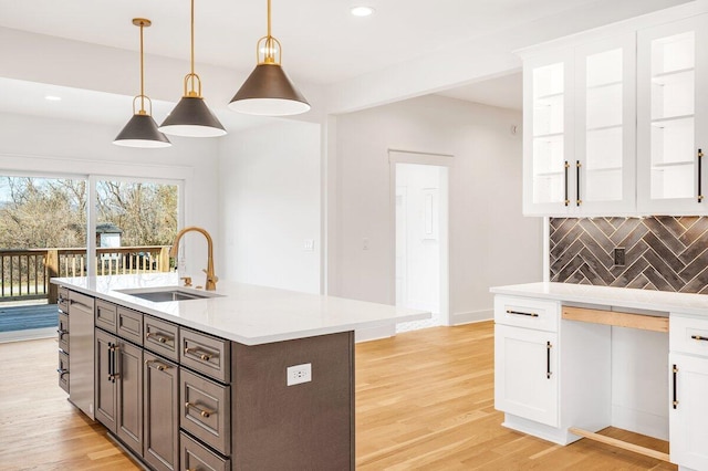 kitchen with white cabinetry, sink, hanging light fixtures, light hardwood / wood-style floors, and dark brown cabinets