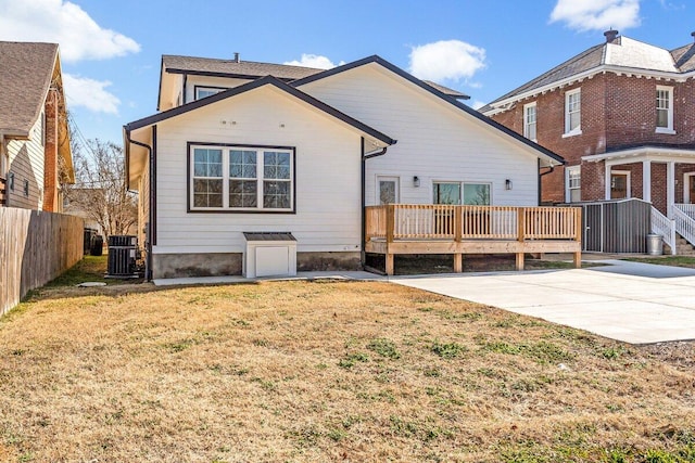 back of property with a wooden deck, a lawn, and cooling unit