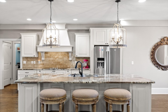 kitchen featuring pendant lighting, sink, stainless steel fridge, and an island with sink