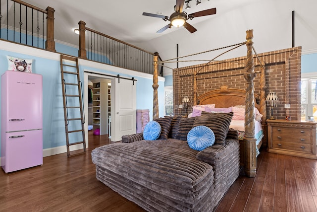 bedroom with crown molding, vaulted ceiling, dark hardwood / wood-style flooring, ceiling fan, and a barn door