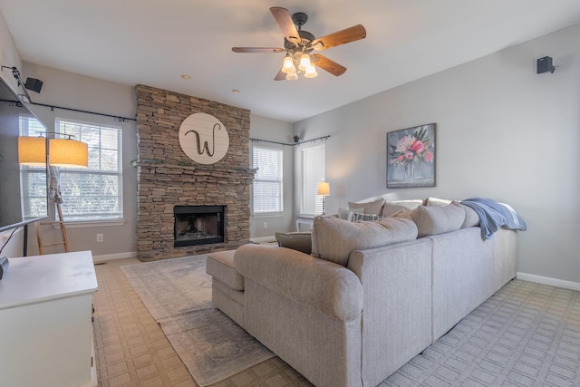 living room with a fireplace, a wealth of natural light, and ceiling fan