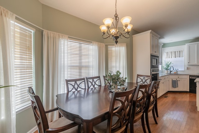 dining area featuring sink, hardwood / wood-style floors, and a chandelier