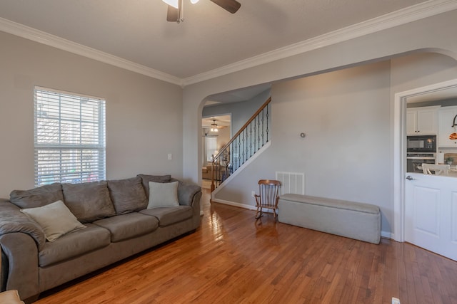 living room with hardwood / wood-style flooring, ornamental molding, and ceiling fan