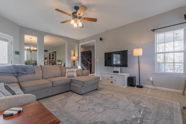 carpeted living room featuring ceiling fan with notable chandelier