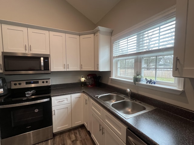 kitchen featuring white cabinetry, lofted ceiling, sink, stainless steel appliances, and dark wood-type flooring