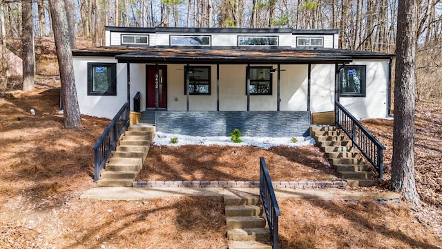 mid-century home featuring stone siding, a porch, stairway, and stucco siding