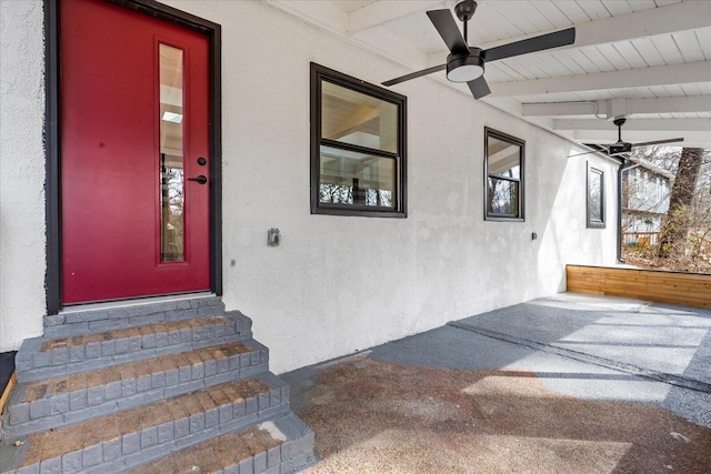 doorway to property with a ceiling fan and stucco siding