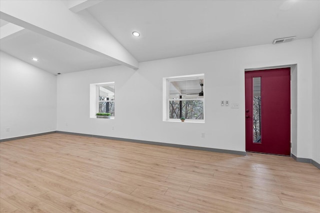 spare room with lofted ceiling, light wood finished floors, baseboards, and visible vents