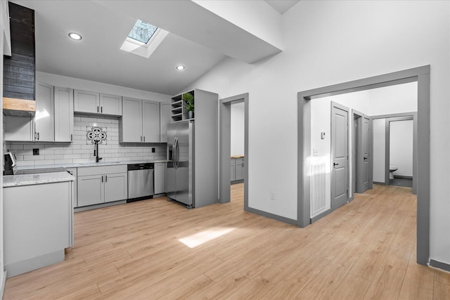 kitchen with a sink, appliances with stainless steel finishes, gray cabinets, and decorative backsplash