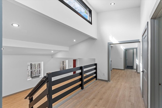 corridor with light wood finished floors, an upstairs landing, and recessed lighting