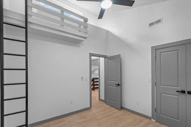 unfurnished bedroom featuring a high ceiling, visible vents, light wood-style flooring, and baseboards