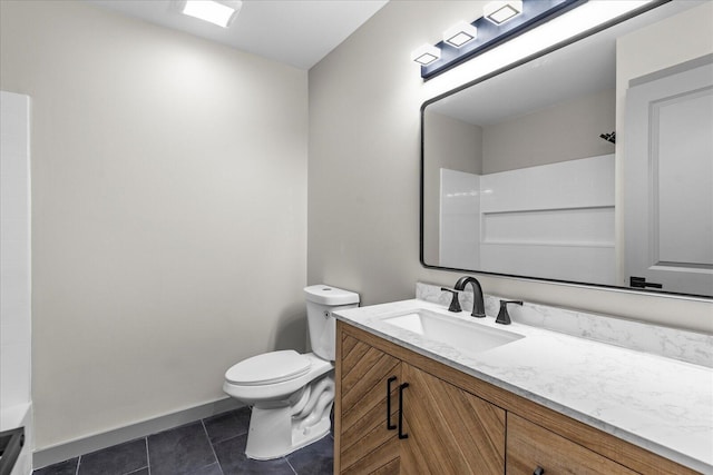 bathroom with tile patterned floors, toilet, vanity, baseboards, and walk in shower