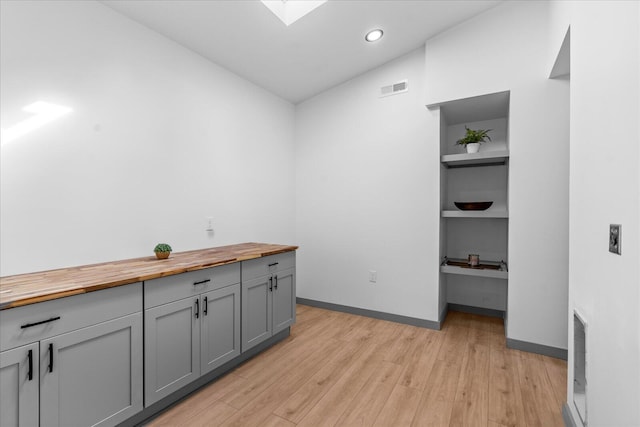 interior space with recessed lighting, visible vents, baseboards, light wood finished floors, and built in desk