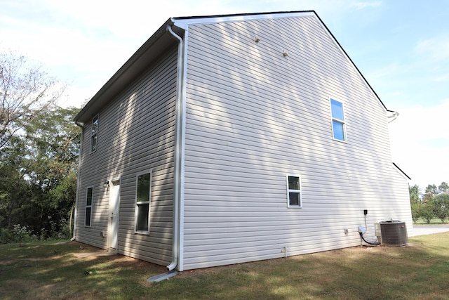 view of side of home with a yard and central air condition unit