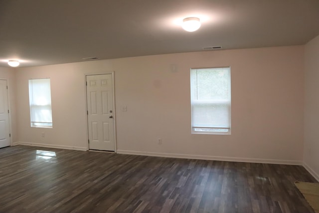 empty room with a healthy amount of sunlight and dark wood-type flooring