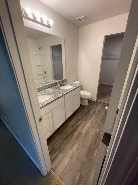 bathroom featuring hardwood / wood-style flooring, vanity, toilet, and walk in shower