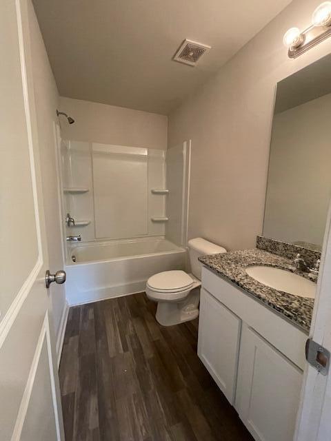 full bathroom with hardwood / wood-style flooring, vanity, bathtub / shower combination, and toilet